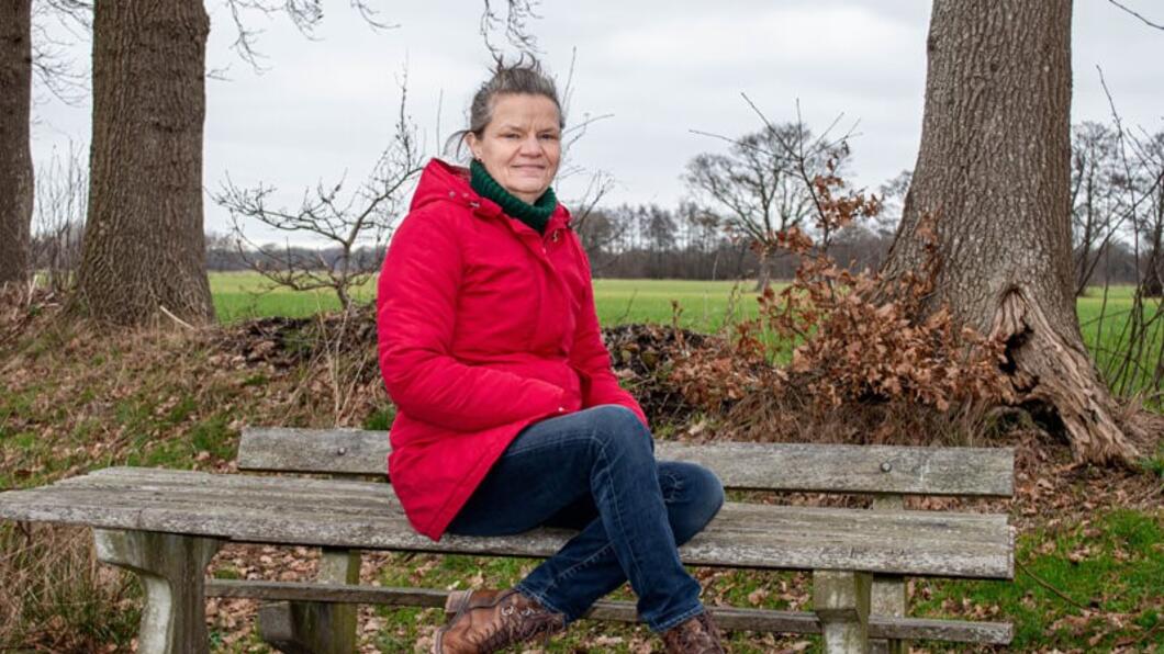 Foto van Gea Bijkerk (Fractievoorzitter) in rode jas op een bankje 