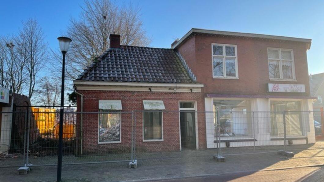 Stenen huisje omgeven met bouwhekken aan de kant van de weg