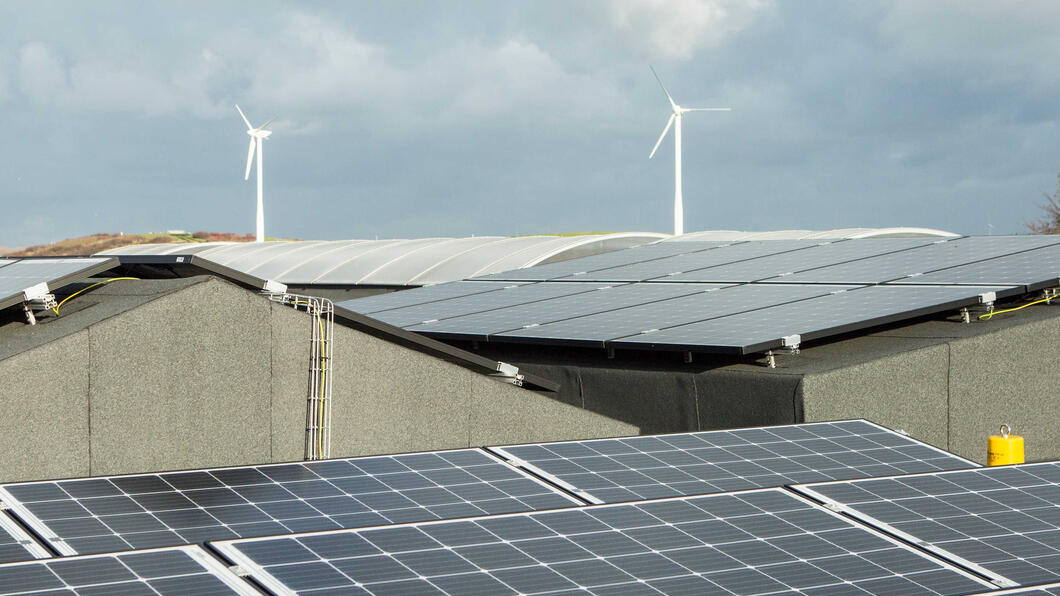 Zonnepanelen op daken met daarachter windmolens 