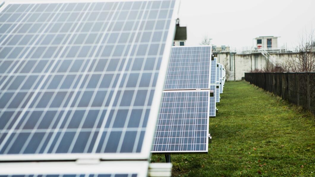 Zonnepanelen met een groen grasveld en wat gebouwen