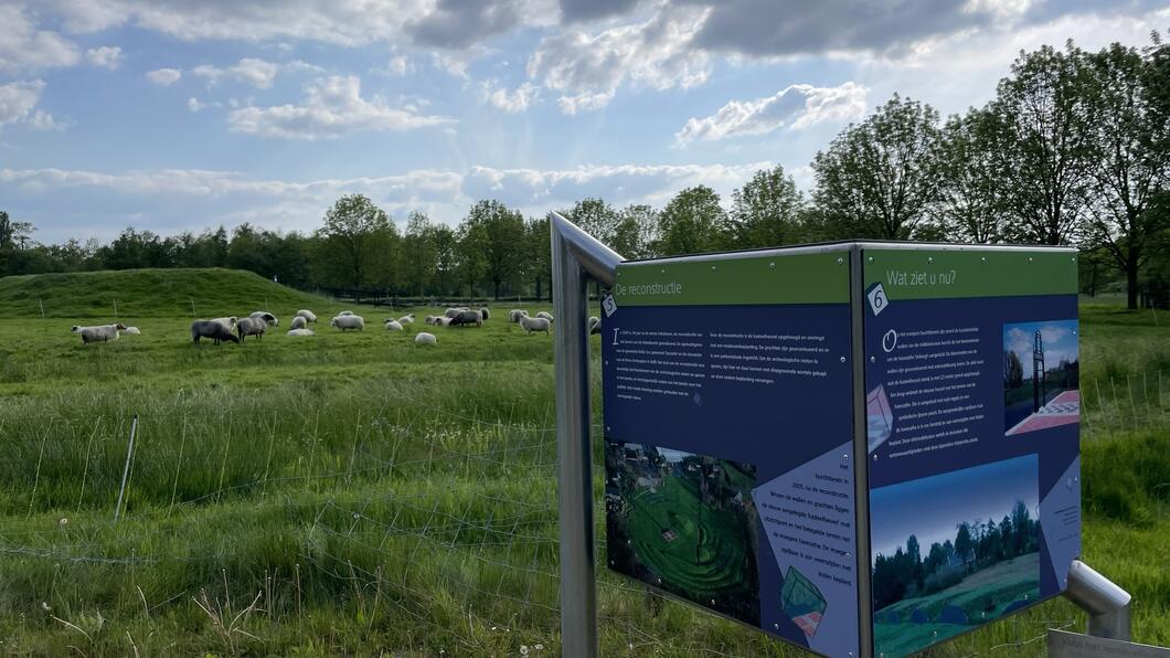 Informatiekubus bij de Waterburcht. Met daarachter schaapjes in een groen weiland