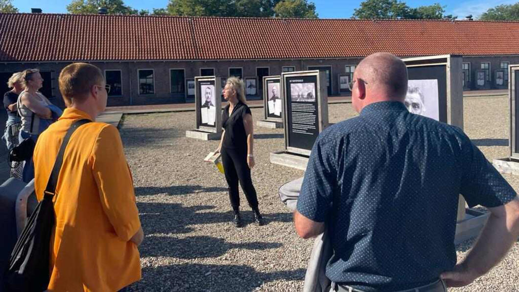 Suzanna Jansen aan het vertellen. De aanwezige mensen staan op grind op een binnenplaatst