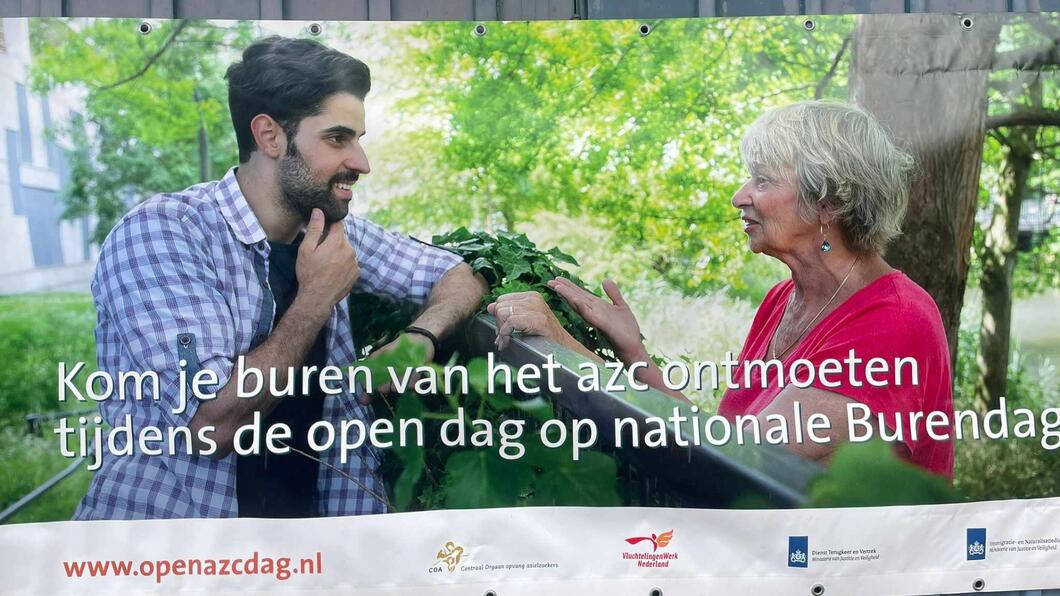 Een banner voor de AZC Burendag