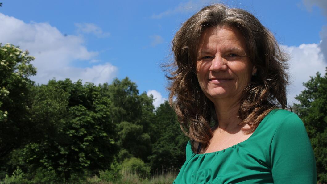 Fractievoorzitter Gea Bijkerk. Gea heeft een groene truitje aan en staat voor enkele bomen