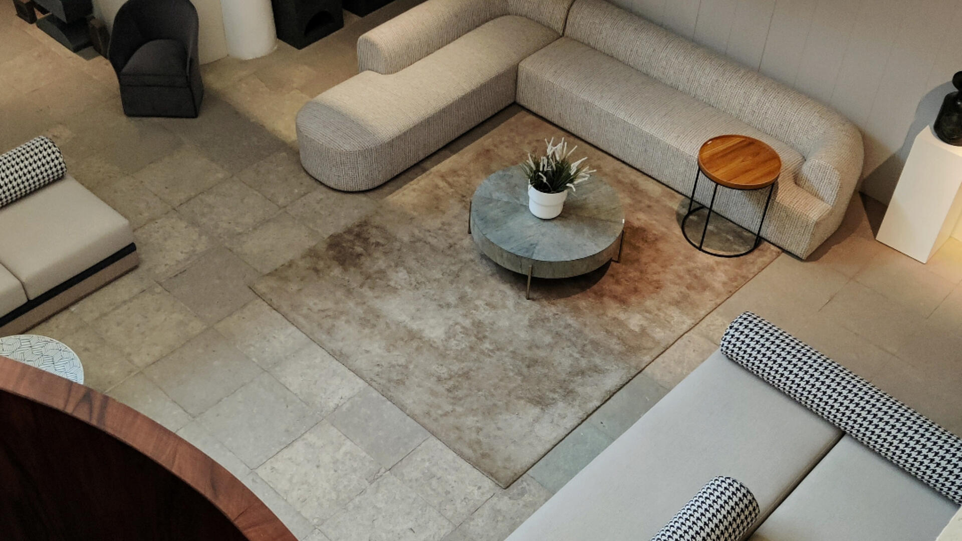Huiskamer met grijs/creme kleurige bank en stoelen met grijs tafeltje en vloerkleed