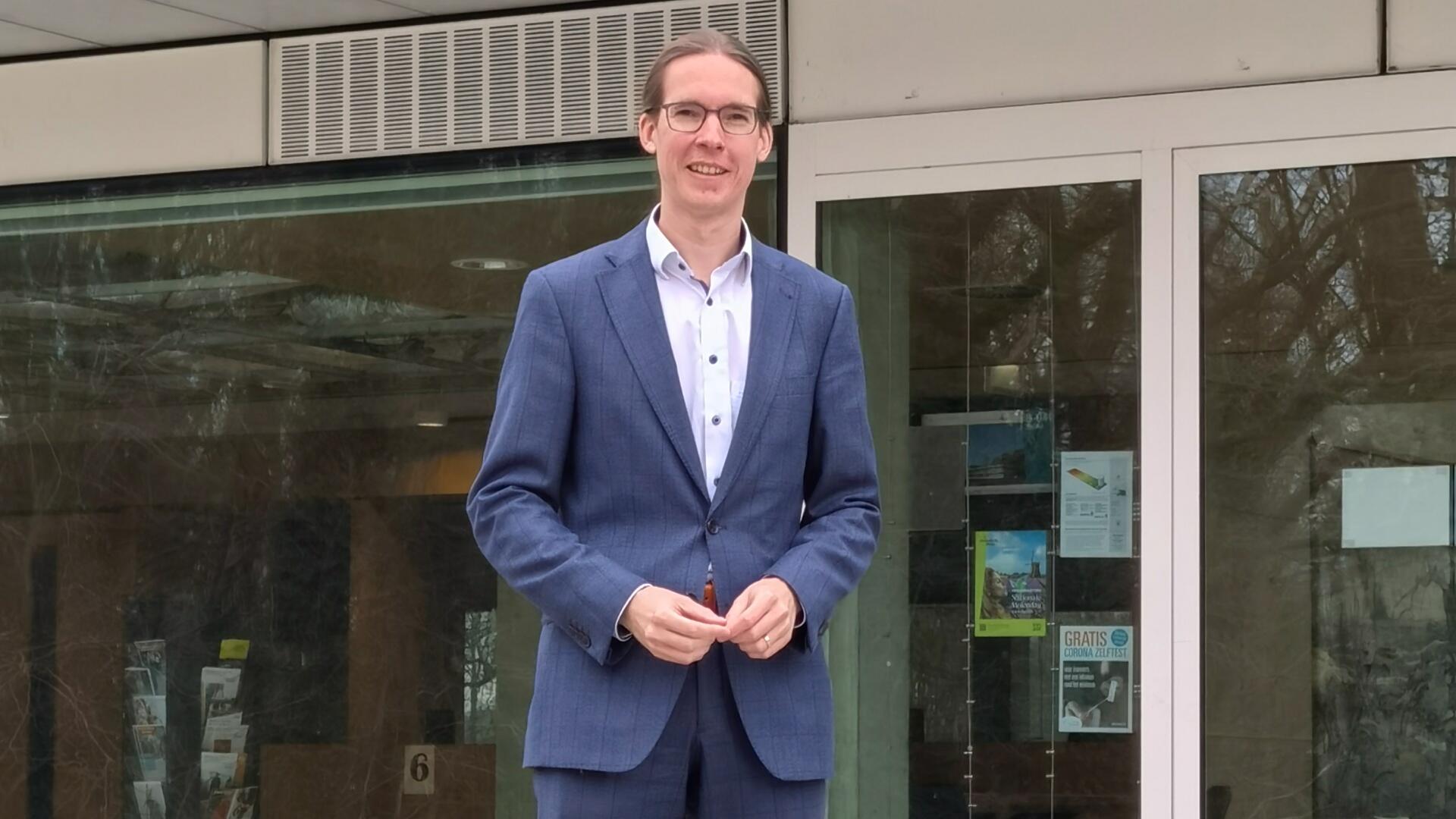 Hans Kuipers in blauw pak, voor het gemeentehuis