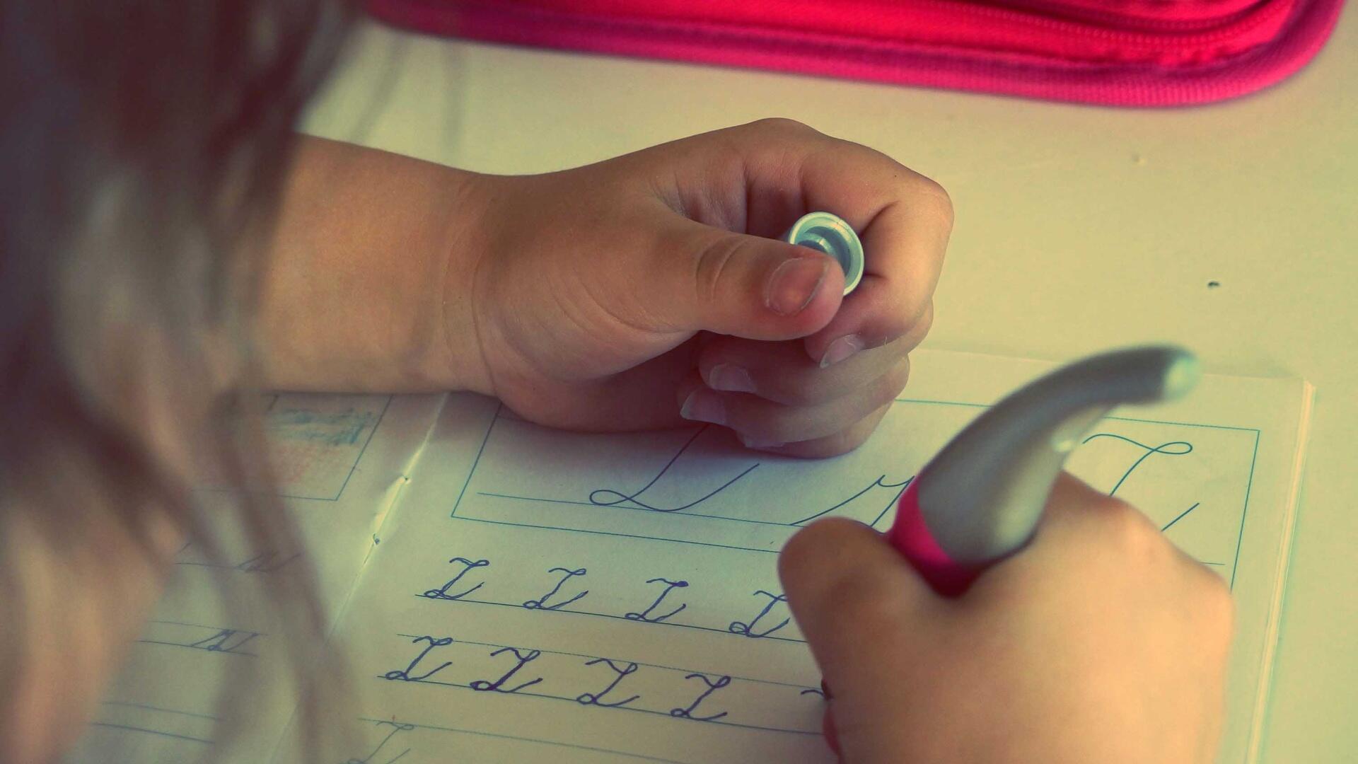 Onderwijs / Leren; een kind leert om met een aangepaste pen te schrijven