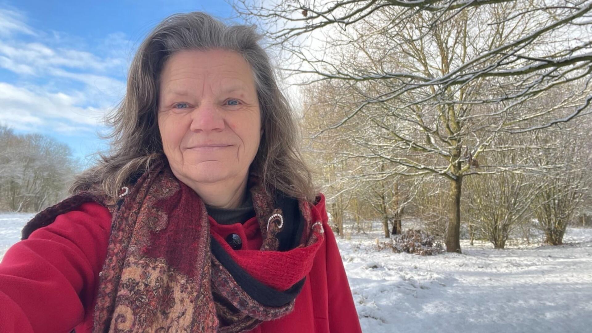 Gea Bijkerk - Eelde. Gea draagt een rode jas, een paarse sjaal en staat in de sneeuw